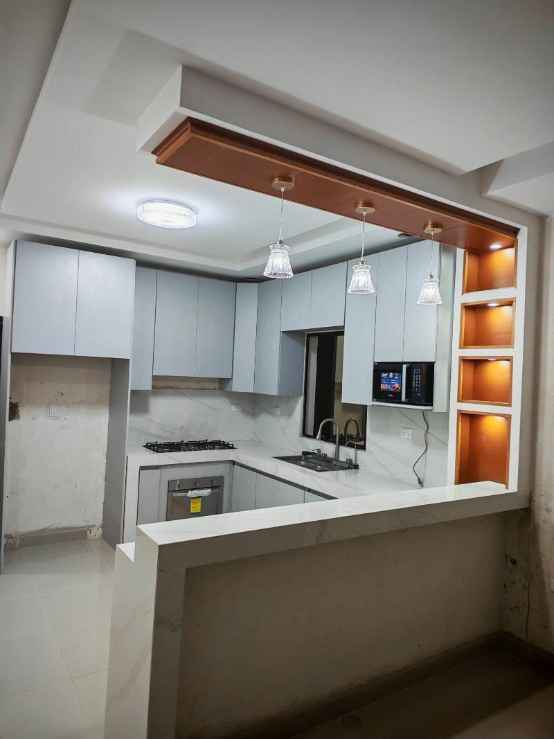 Cocina moderna de melamina con barra de cuarzo e iluminación en Managua